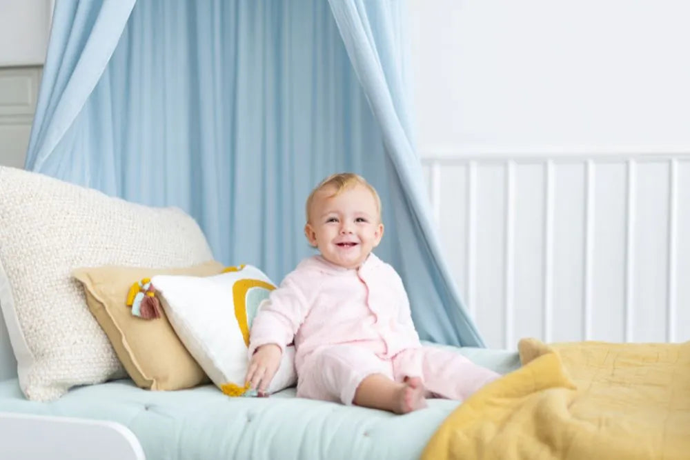bébé se tient assis tout seul dans son lit