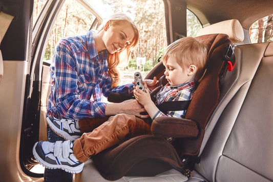 une maman prépare son bébé pour un trajet en voiture