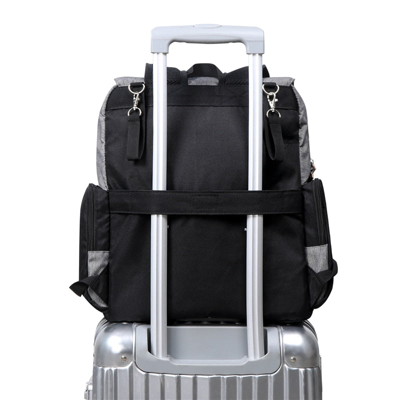 sac à dos à langer noir avec sur une valise à roulette